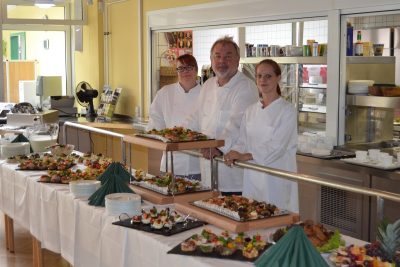 Beschäftigte Menschen im Gruppenfoto vor einem Buffet