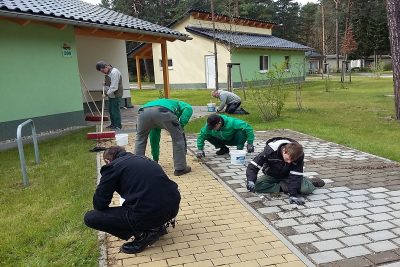 Eine Gruppe beschäftigter Menschen beim Unkraut zupfen